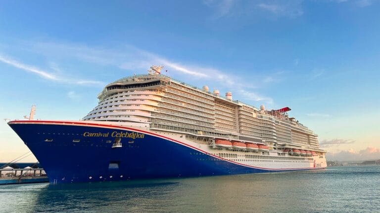 This is the header in Packing Tips for Your First Carnival Cruise Adventure. Large cruise ship named "Carnival Celebration" docked under a clear blue sky. The ship's massive structure and lifeboats are visible, suggesting luxury and adventure.