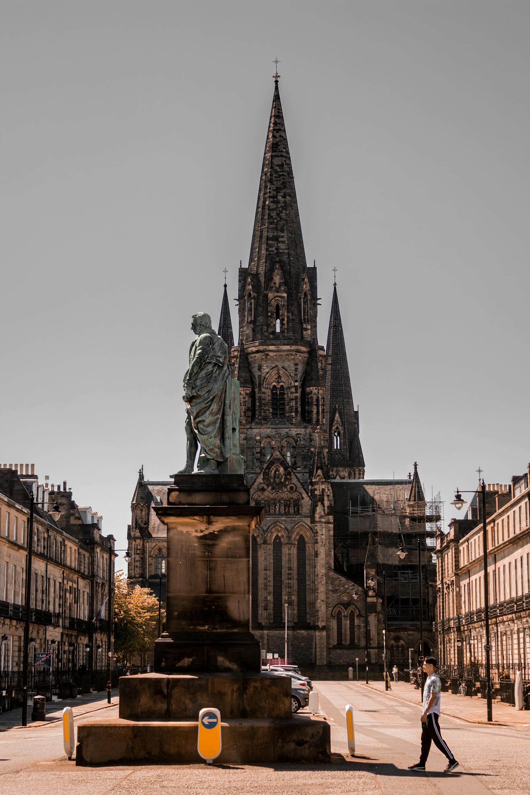 A majestic gothic cathedral in Edinburgh with a historical statue in the foreground.