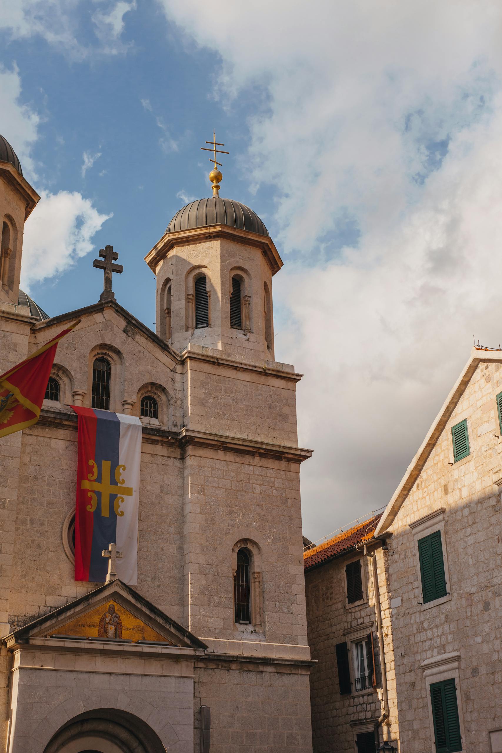 Elegant stone church facade with flags, architectural heritage in Montenegro's old town.