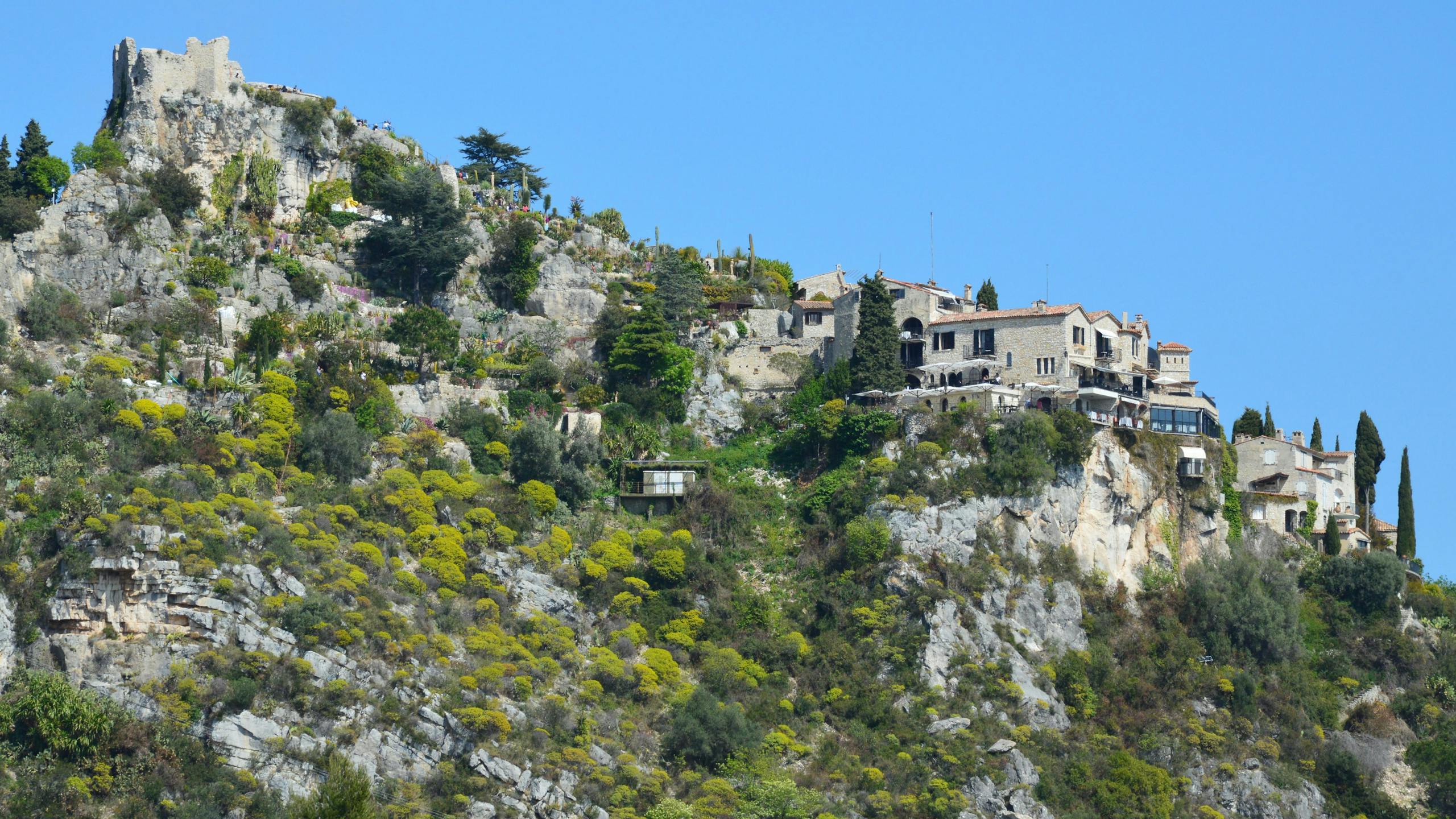 Stone houses perched on a rocky hill under a clear blue sky.