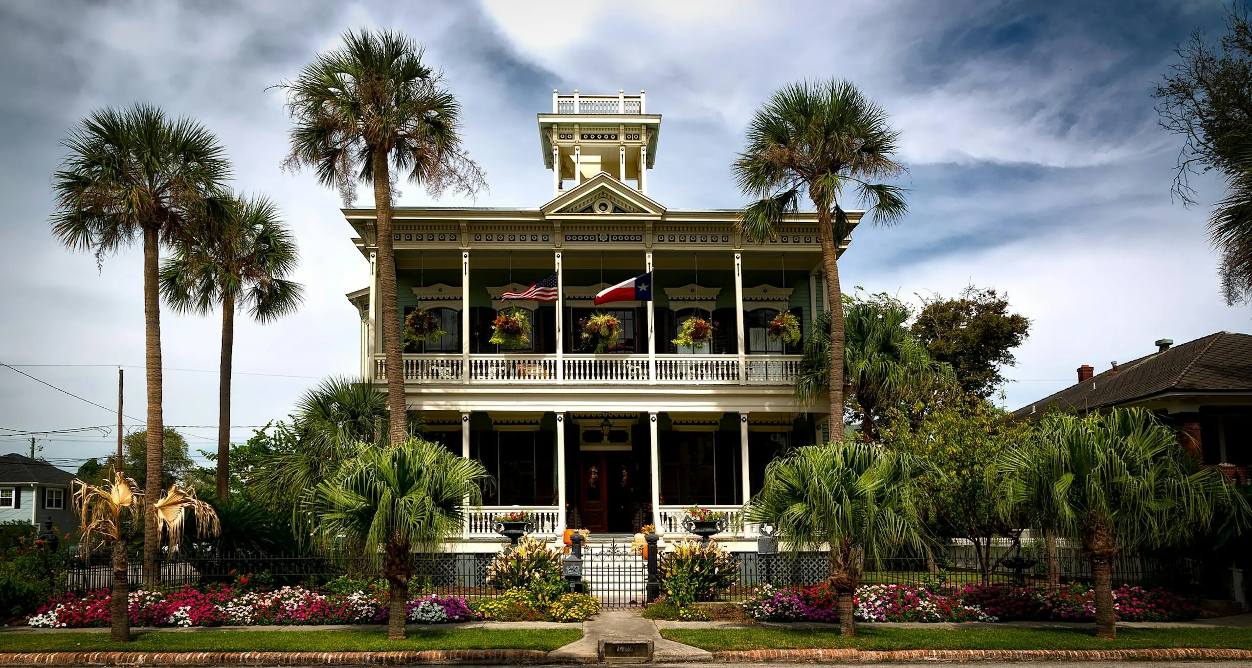 Stunning view of a historic mansion with lush gardens and palm trees in Galveston, Texas.