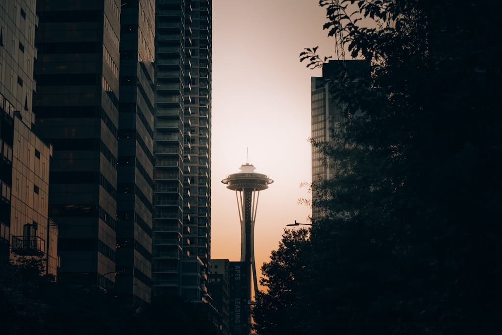 The Space Needle framed between modern skyscrapers at sunset in Seattle.