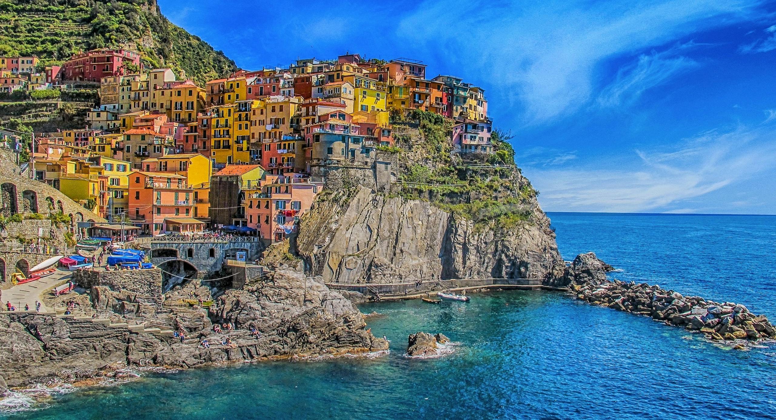 Vivid view of Manarola's colorful houses perched on cliffs, overlooking the blue sea.