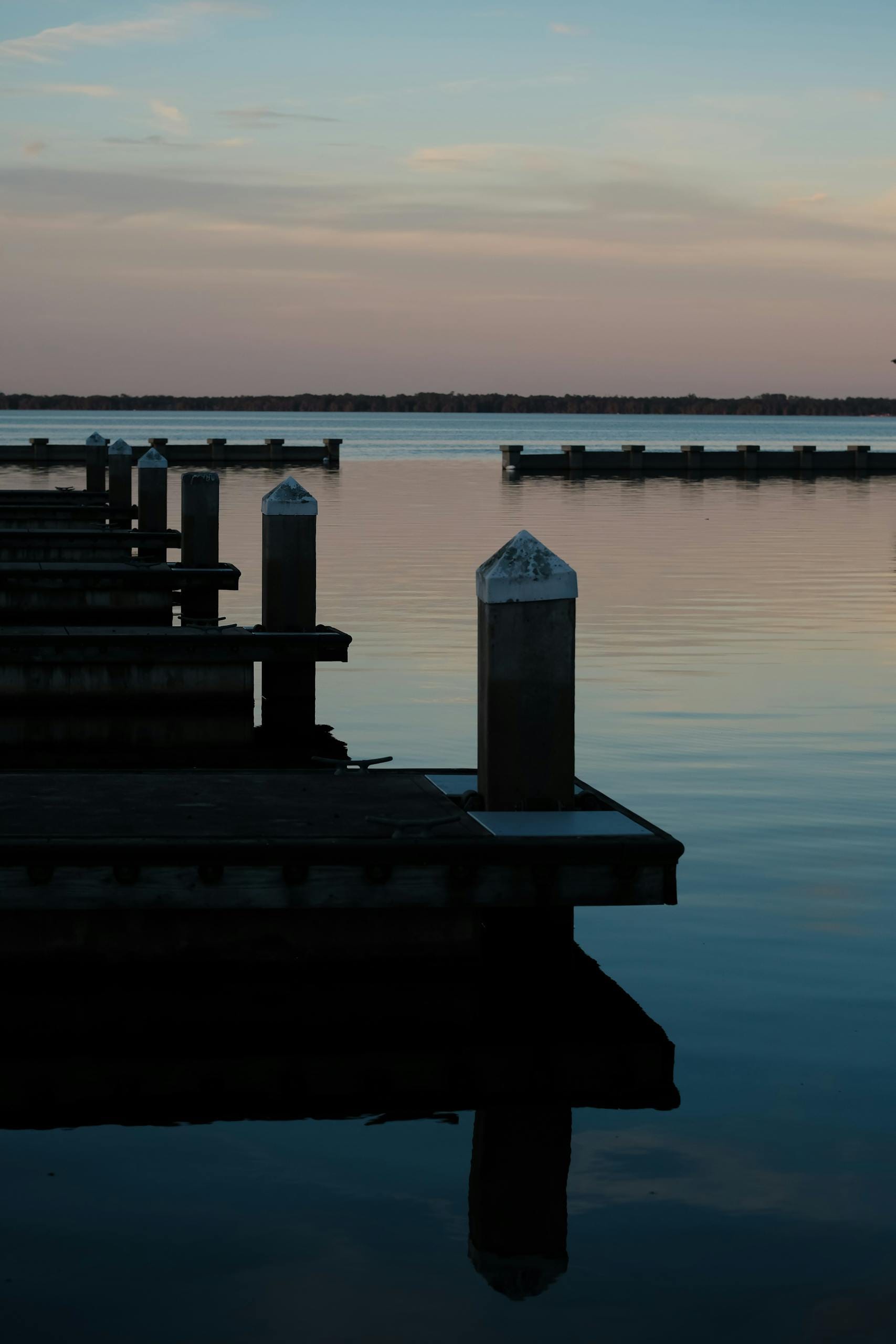 Tranquil evening view of an empty pier reflecting on calm waters at sunset.