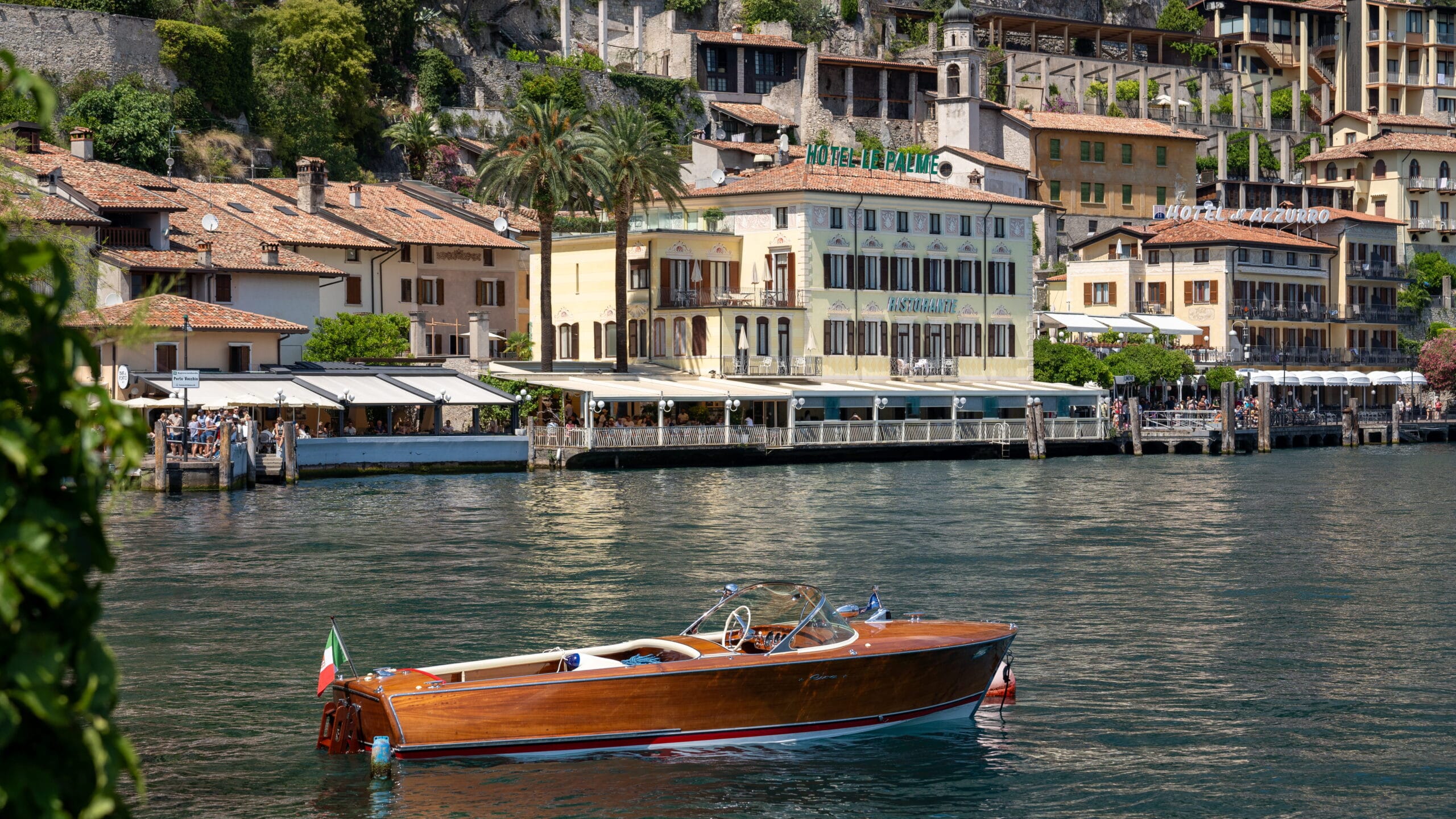 Lake Garda lakeside town with a classic wooden boat, Italy