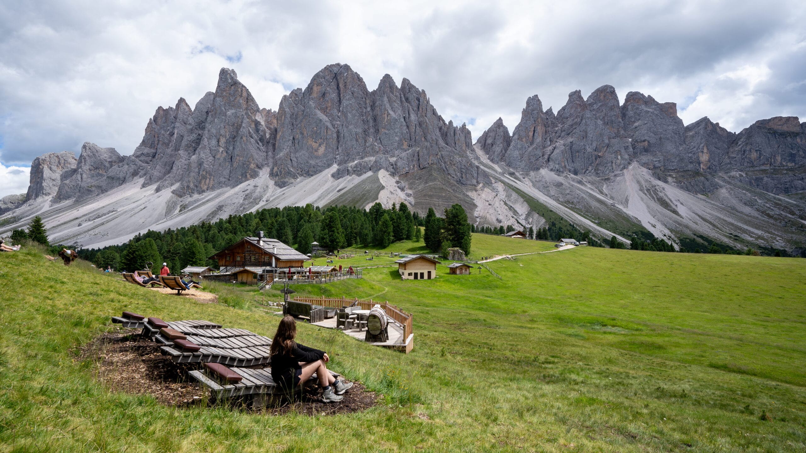 Giant wooden lounge chairs at Geisler Alm facing the Odle peaks, Val di Funes, Dolomites