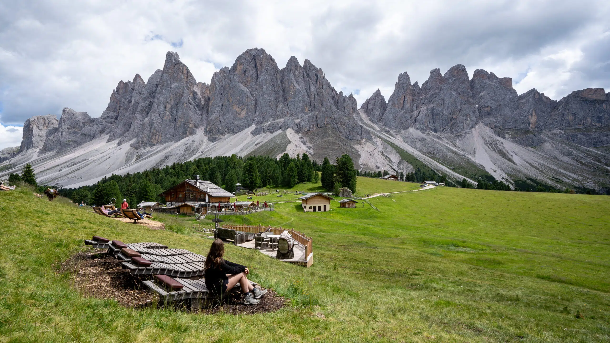 Giant wooden lounge chairs at Geisler Alm facing the Odle peaks, Val di Funes, Dolomites