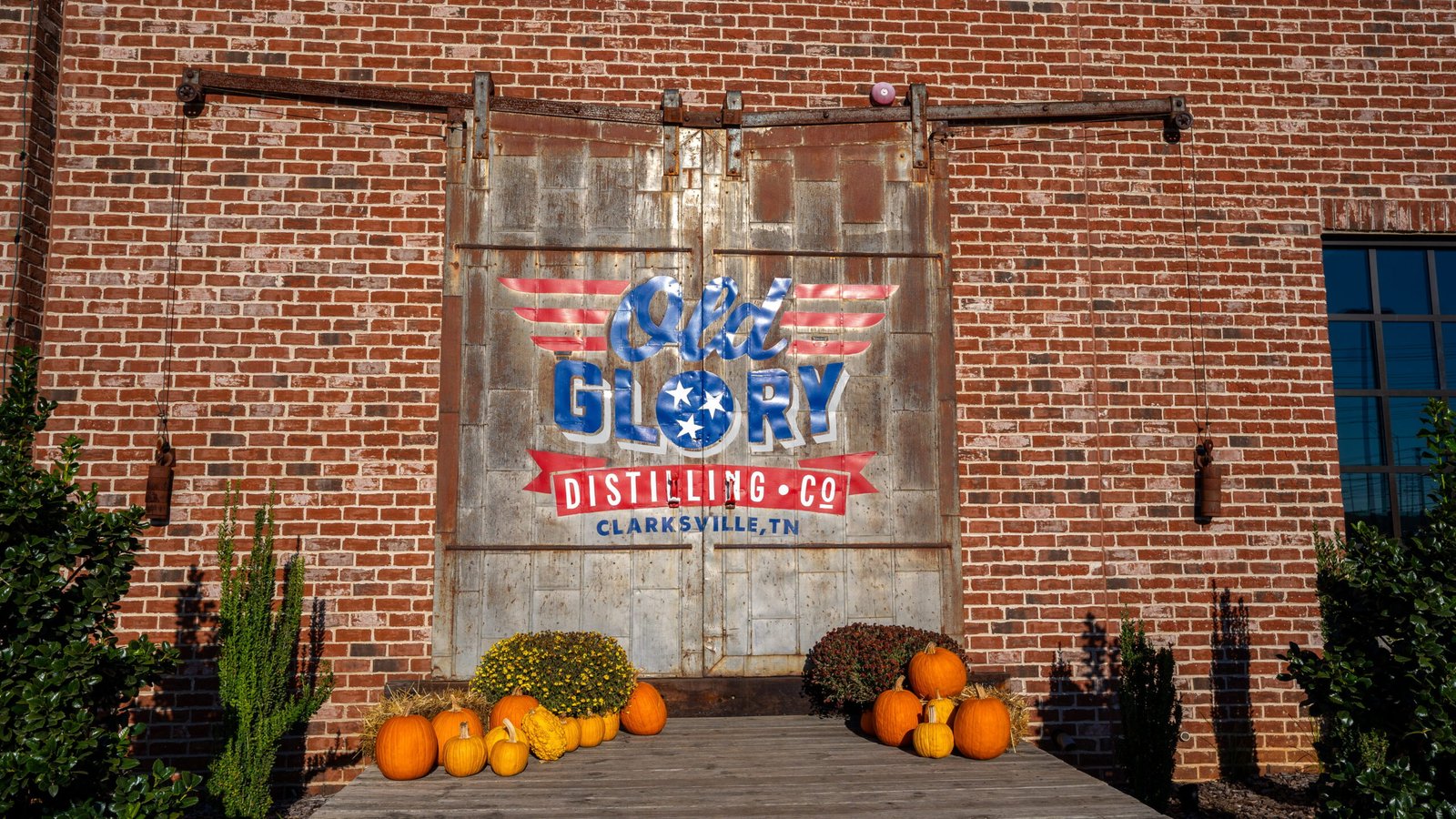 Old Glory Distilling Co. sign on a brick wall with fall pumpkins at Old Glory restaurant in Clarksville, TN