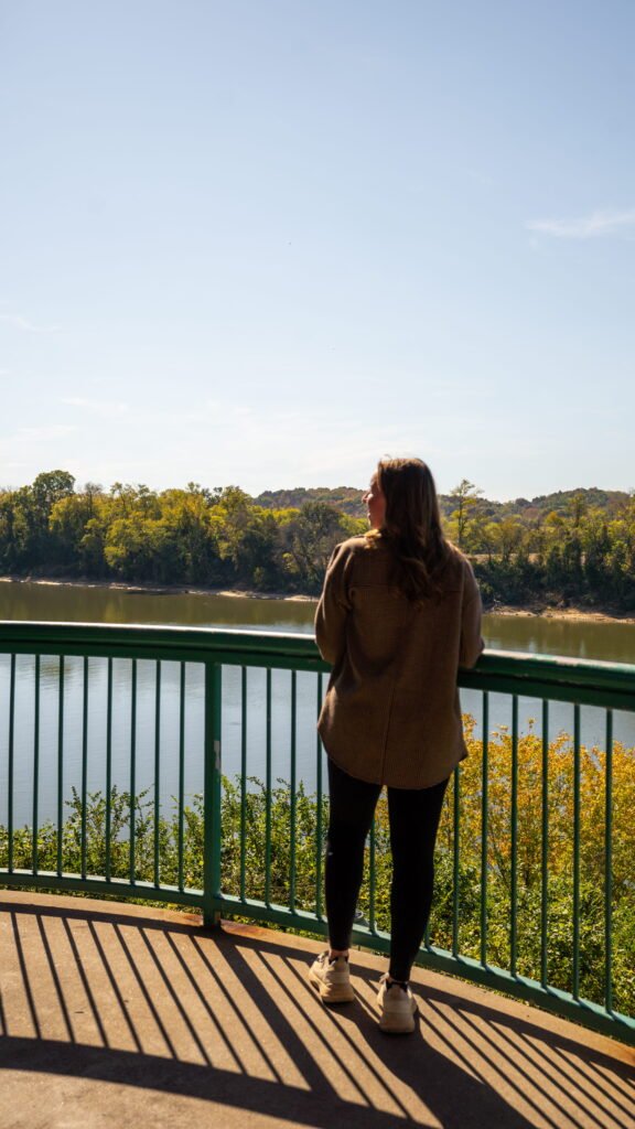 Woman looking out over the Cumberland River from a green railing on the Clarksville Riverwalk on a day trip from Nashville