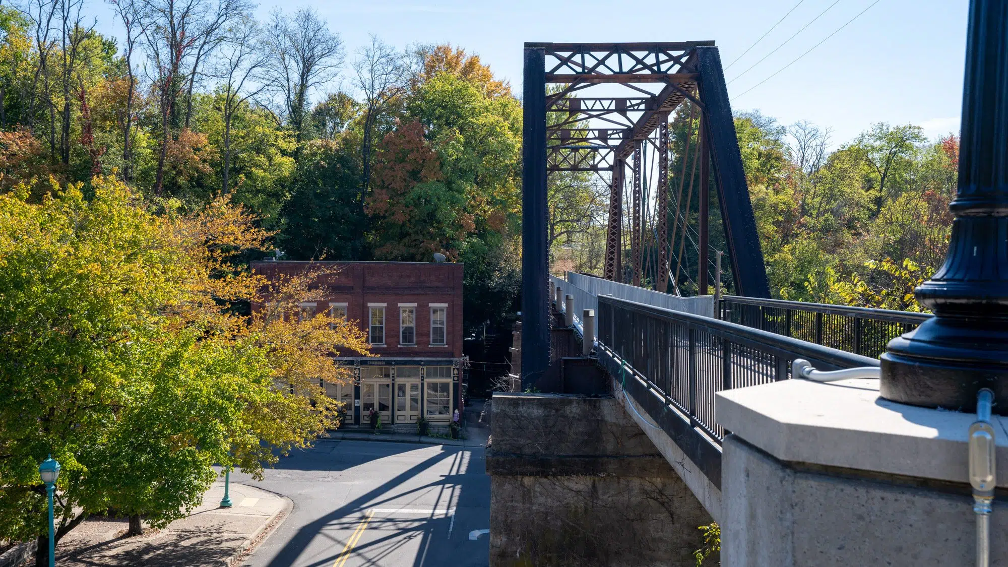 Historic iron truss pedestrian bridge surrounded by fall trees in downtown Clarksville