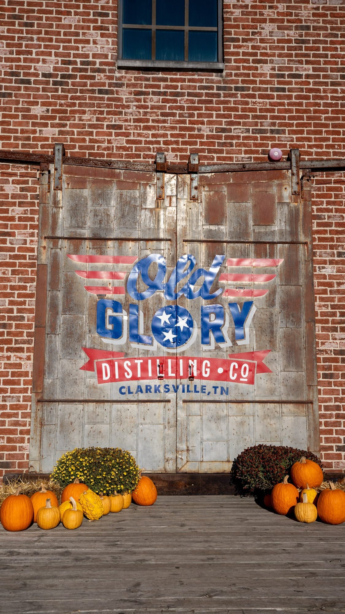 Old Glory Distilling Co. sign on a barn door decorated with fall pumpkins in Clarksville, TN